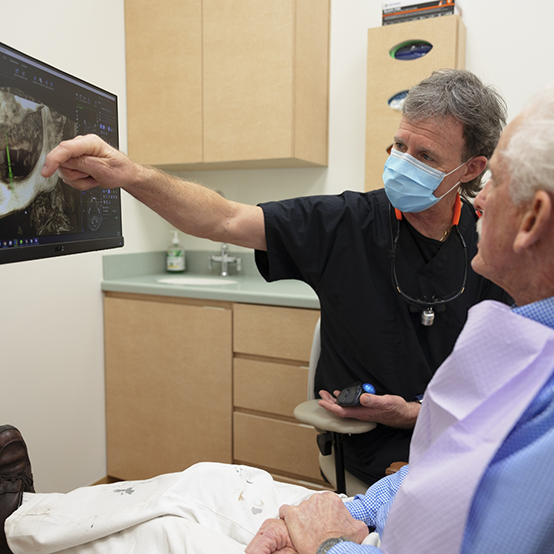 Dentist showing a patient a screen with a scan of their jawbone