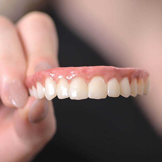 Hand holding a full upper denture