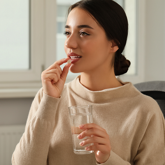 Woman taking a pill with a glass of water