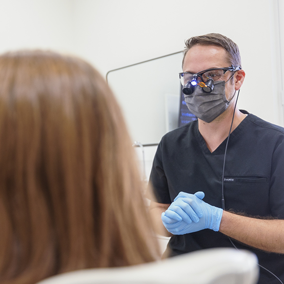 Dentist touching a screen showing a digital model of an arch of teeth