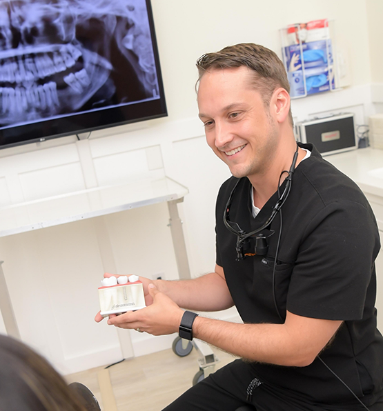 Doctor Heimerdinger showing a model of a dental implant to a patient