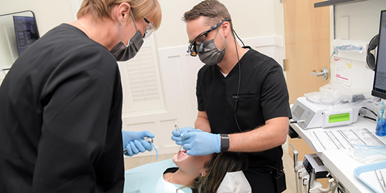 Dentist wearing dental binoculars while treating a patient