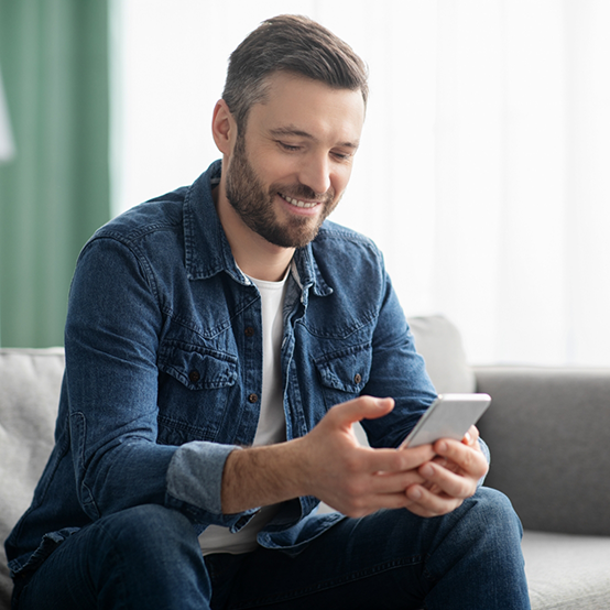 Man sitting on couch and typing on his phone